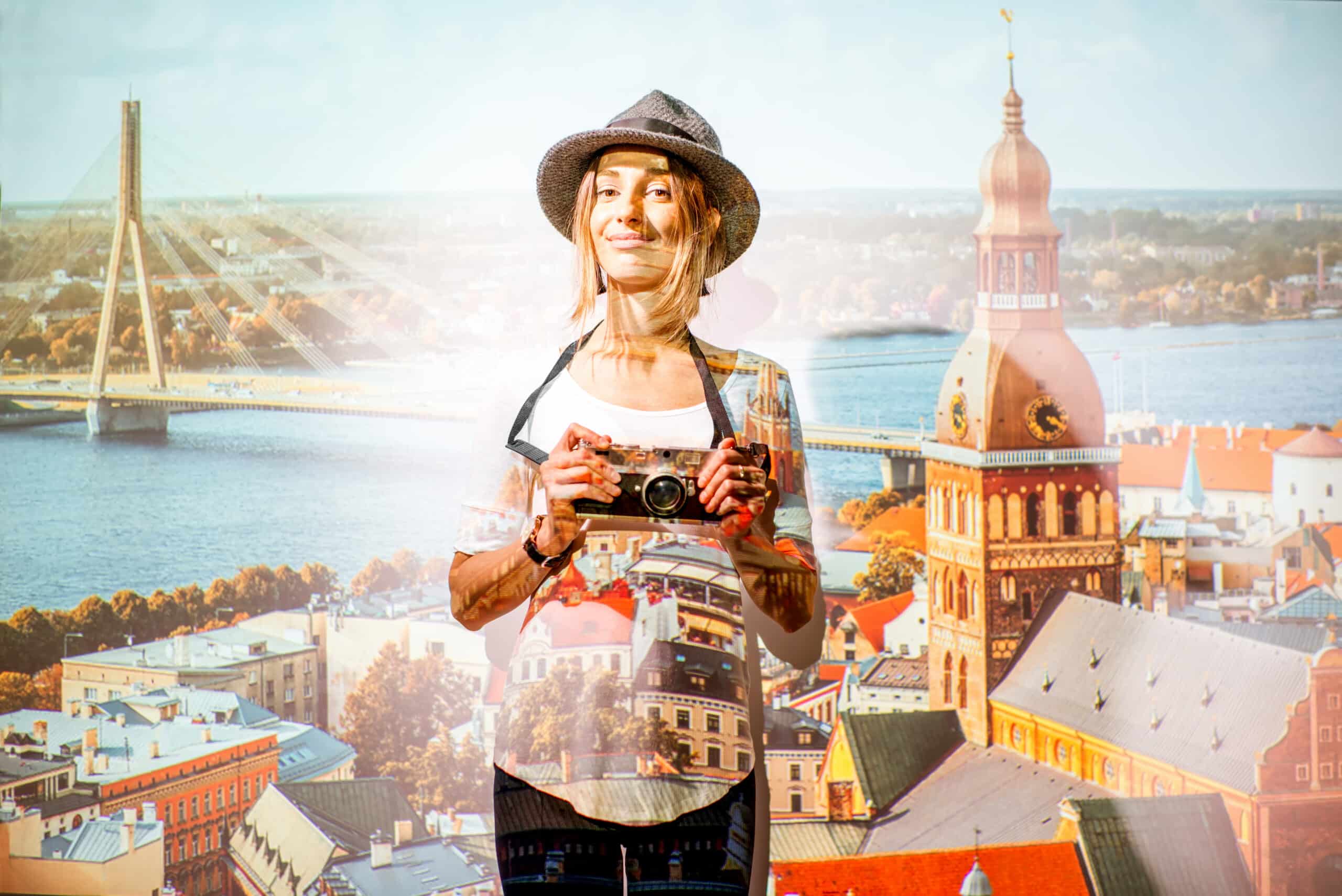Portrait of a young woman traveler with photocamera with projected image of Riga cityscape